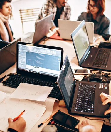 Team working with laptops on technical planning and collaboration for business software solutions.